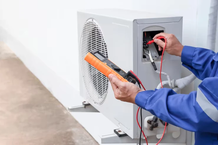 Technician checking outdoor air conditioner electrical components with a clamp meter