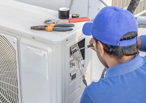HVAC technician servicing an outdoor air conditioner electrical panel