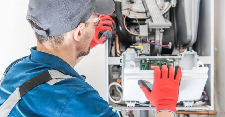 Heating service technician inspecting the components of an indoor heating unit